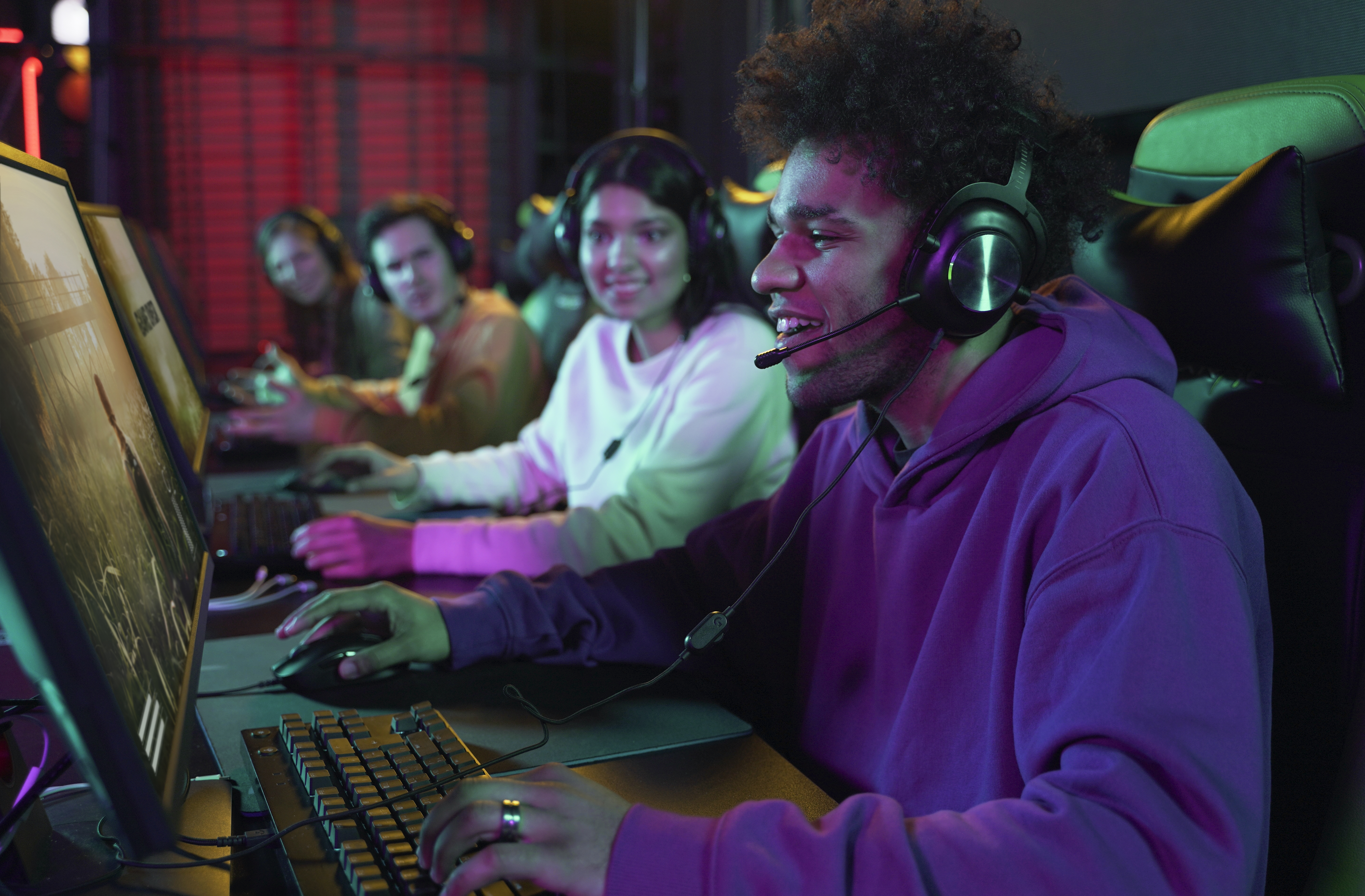 group of gamers wearing headphones intensely play at their computers