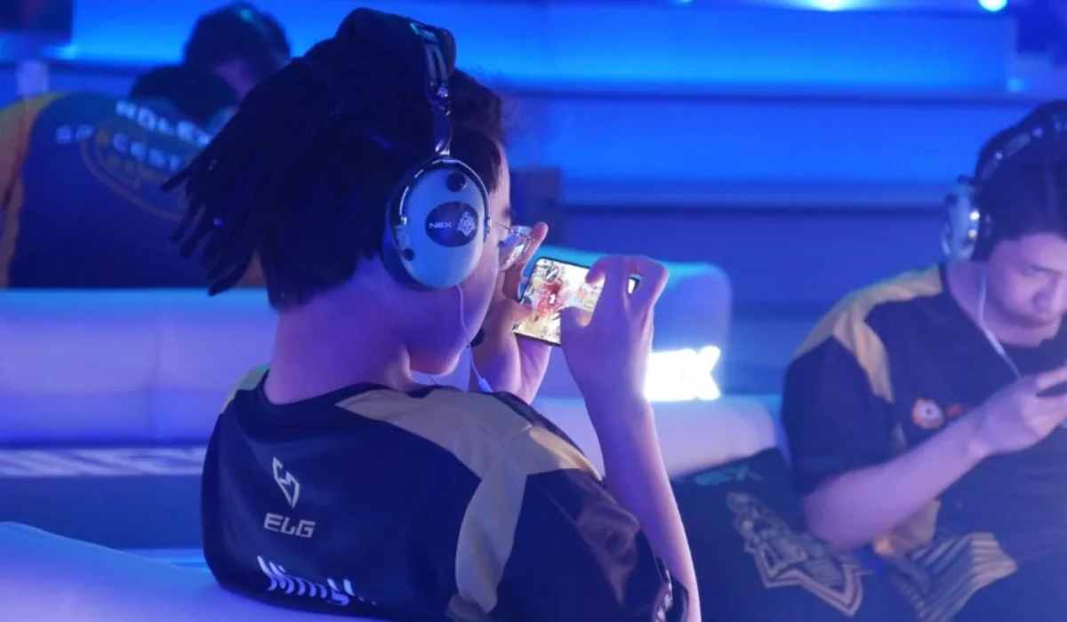 gamer wearing headphones focuses on their mobile device