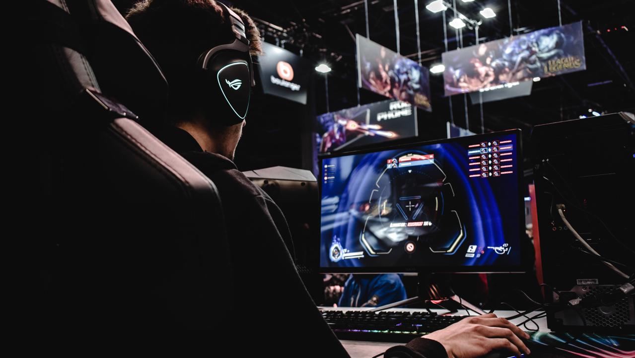 gamer wearing glowing headphones plays on a computer